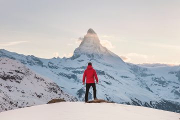 Un homme de so face à une montagne enneigée