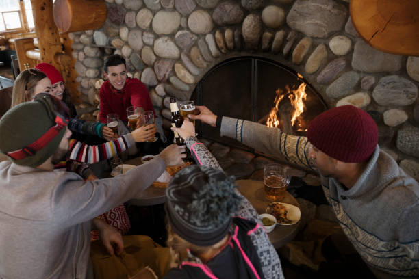 Groupe d'amis en train de boire et manger près d'une cheminée dans un chalet de montagne