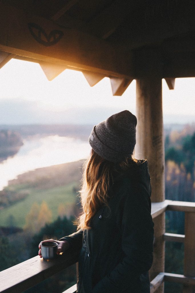 Jeune femme déjeunant face à la vue sur les montagnes depuis un balcon de chalet en bois