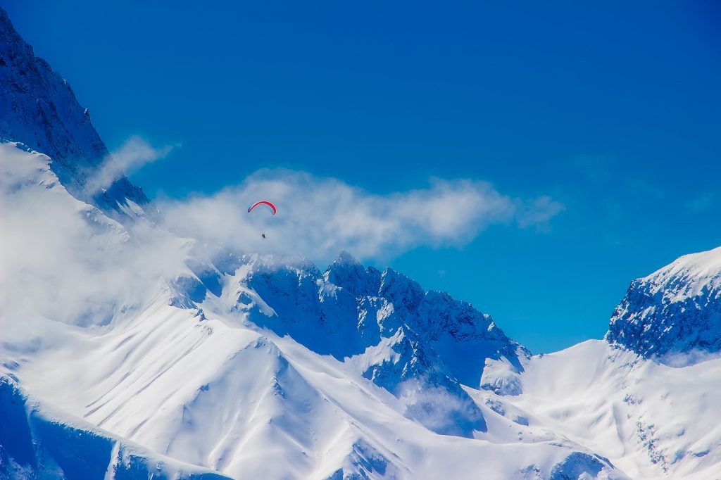 Montagne enneigée avec un parapente en premier plan