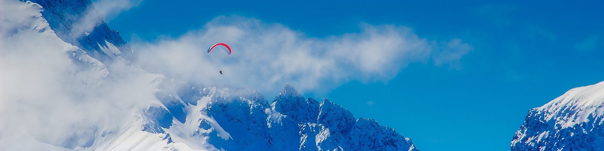 Montagne enneigée avec un parapente en premier plan