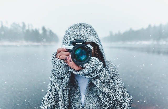 photo avec fond de neige et une personne avec une appareil photo de face